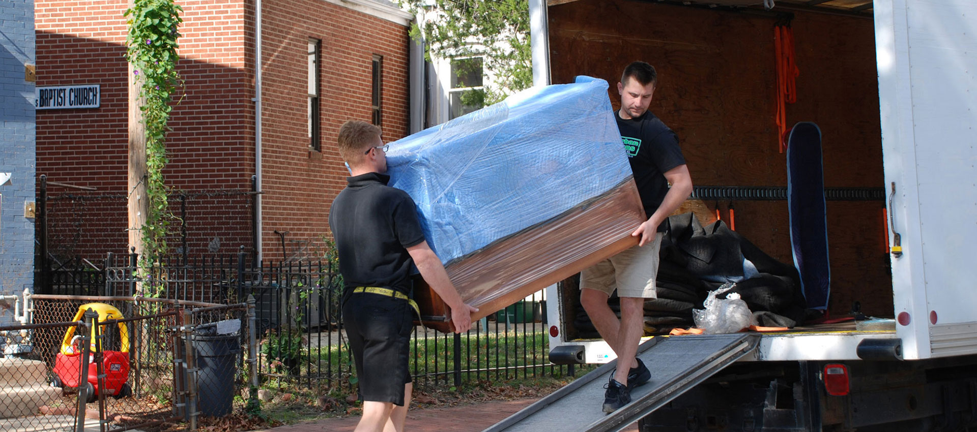 Movers lift furniture into Box Truck Couriers moving truck.
